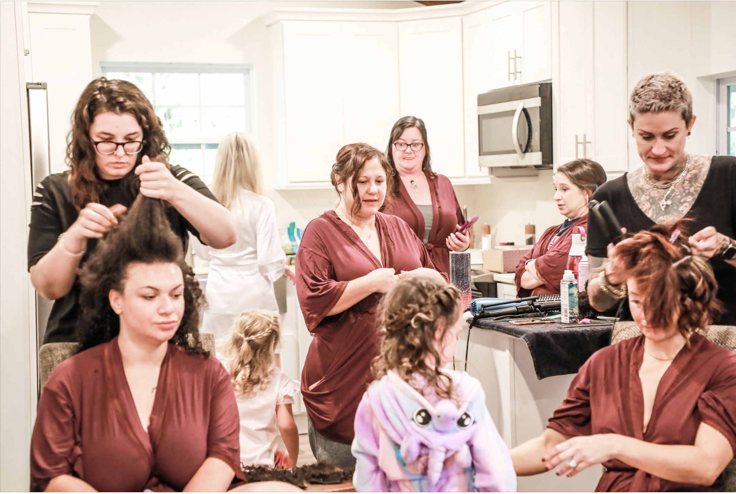 Stylist applying hair extensions to a client with long, reddish-brown hair at Keenan Salon.