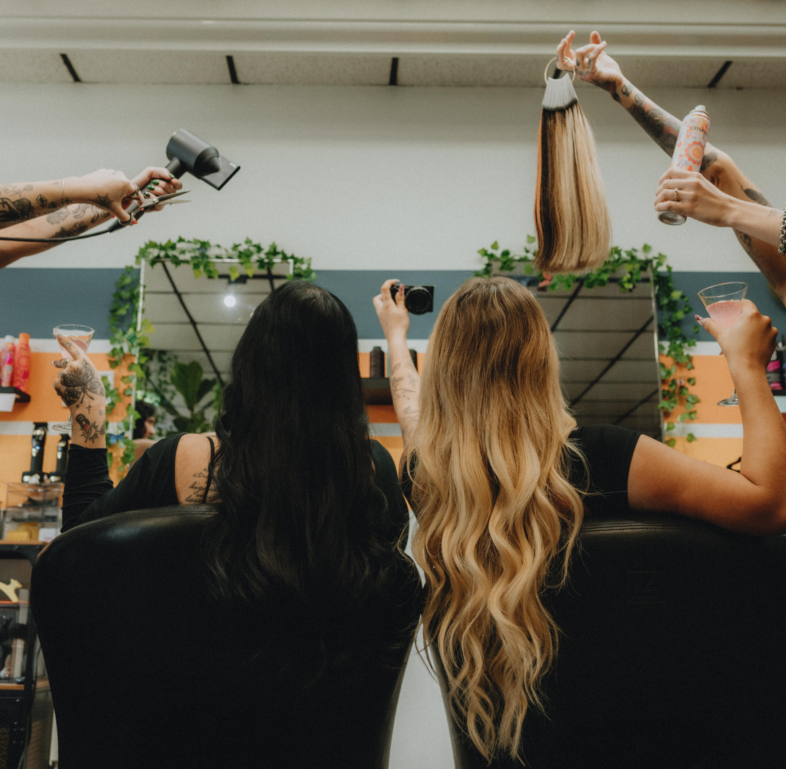 Stylist applying hair extensions to a client with long, reddish-brown hair at Keenan Salon.