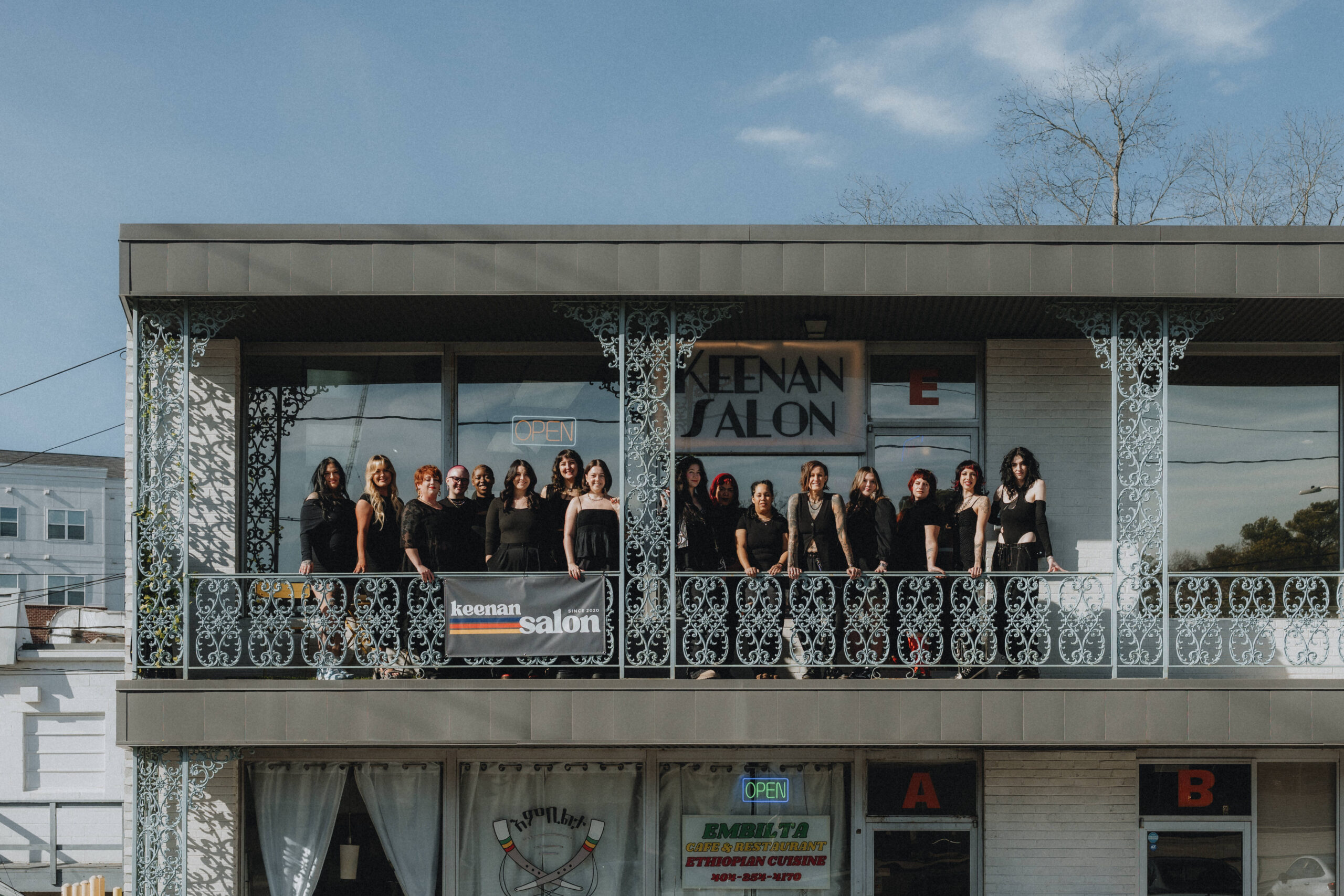 Keenan Salon team celebrating with arms raised, holding a "Best of Georgia 2024" award from Georgia Business Journal.
