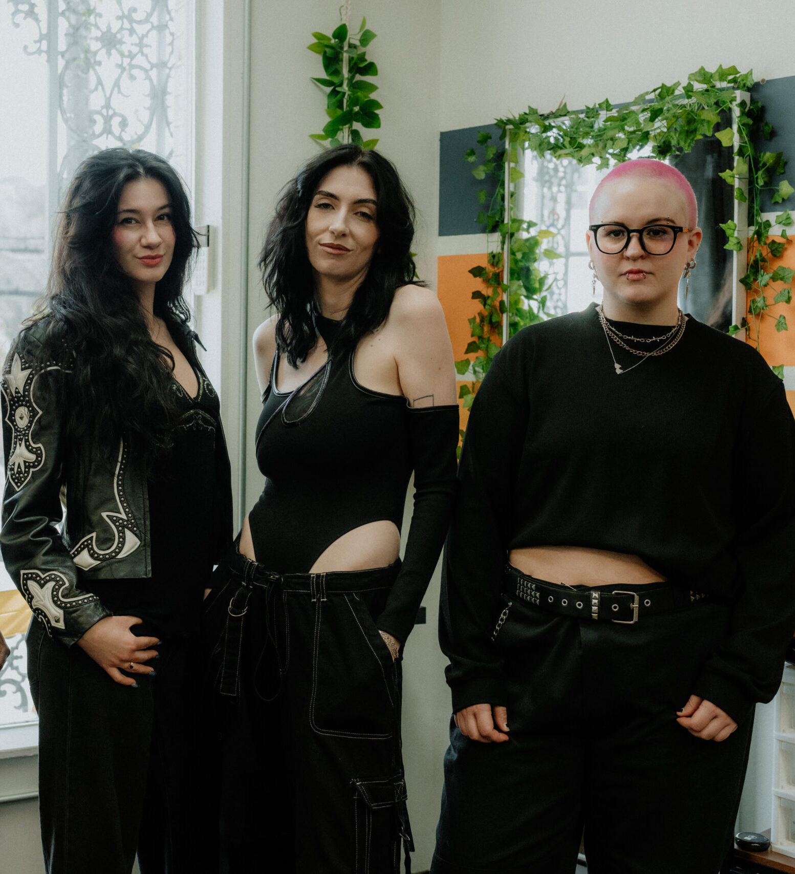 The Keenan Salon team posing together in the salon, featuring stylists dressed in black with a backdrop of colorful hair products and plants.