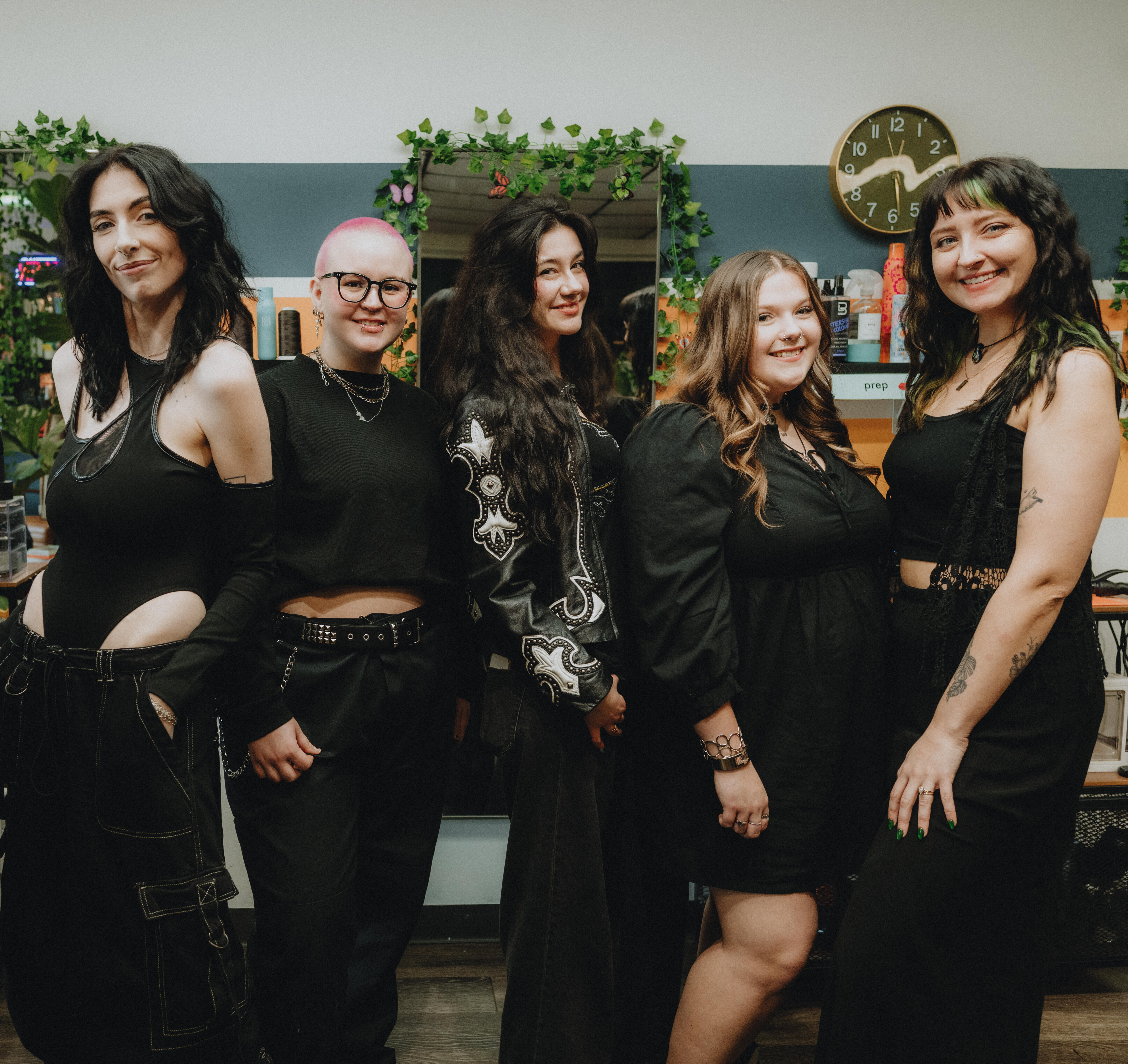 Keenan Salon 2026 The Keenan Salon team posing together in the salon, featuring stylists dressed in black with a backdrop of colorful hair products and plants.
